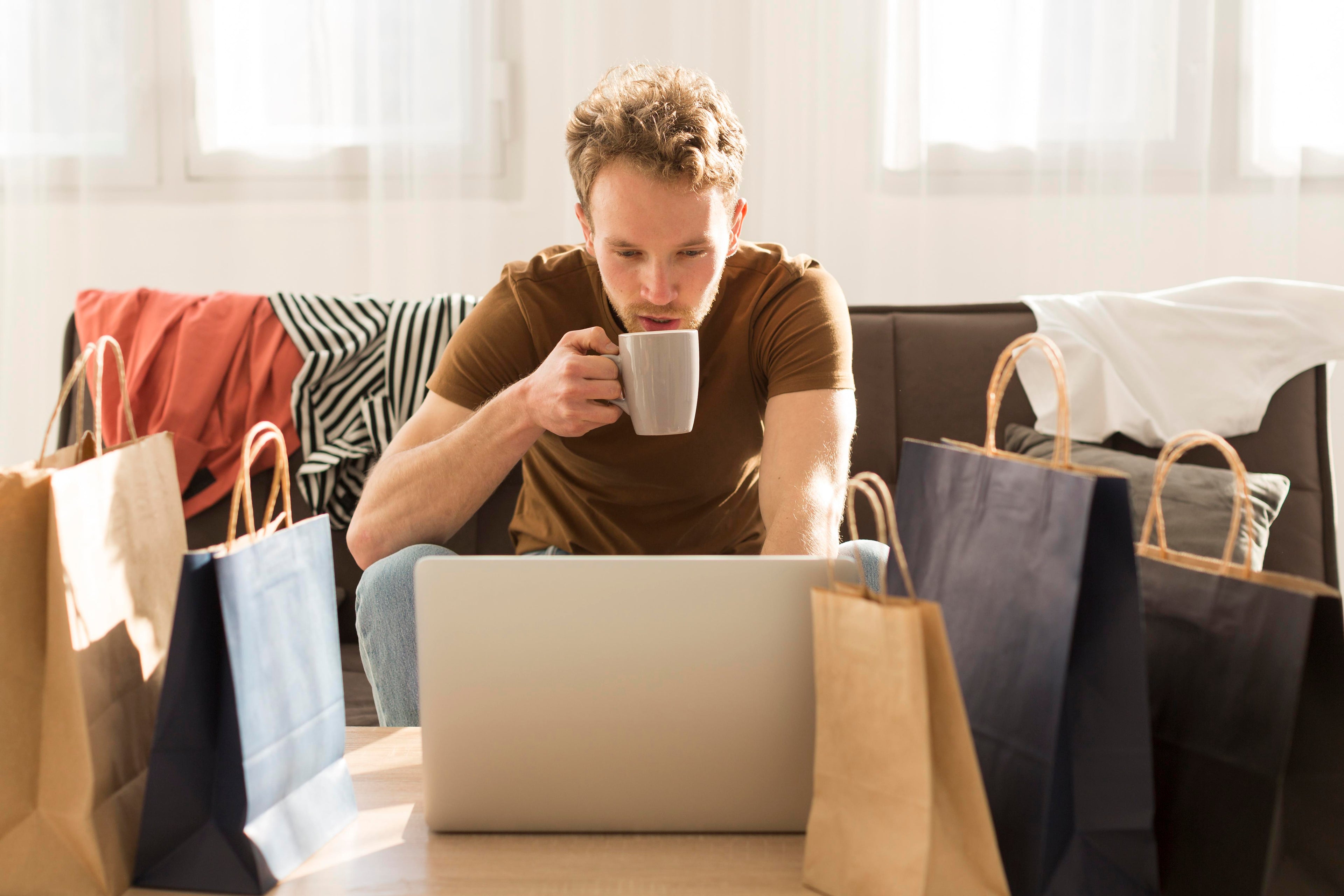 Man drinkt koffie tijdens online winkelen